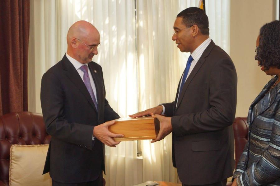 Mr. Bruno Pouezat, UN Resident Coordinator, presents credentials and receives a gift from Prime Minister Andrew Holness and Permanent Secretary, Ms. Elaine Foster-Allen (right).